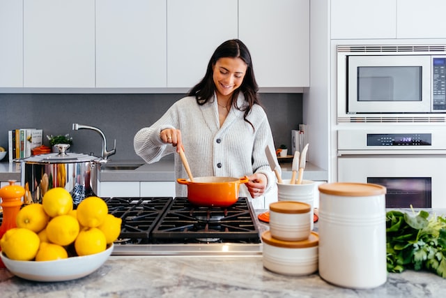 smiling-person-stirring-an-orange-pot-on-a-stove-in-a-clean-kitchen