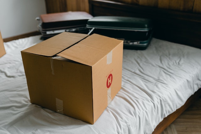 a-moving-box-and-suitcases-sitting-on-a-bed